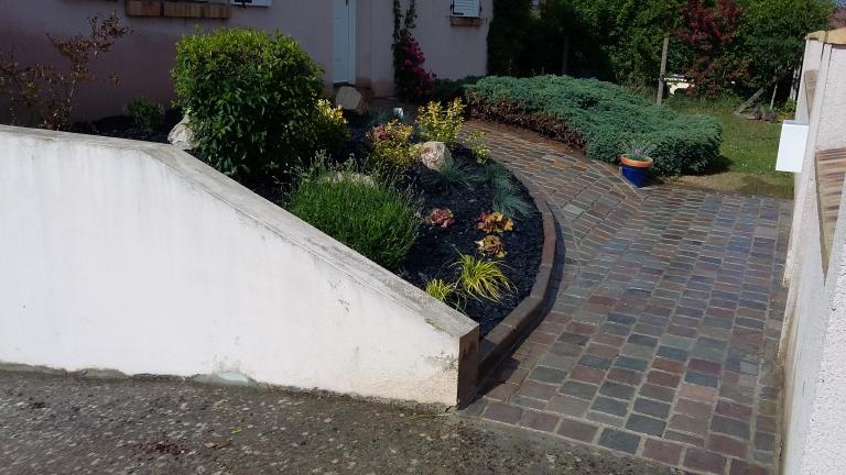 Allée piétonne en pavés de rue en grès et massif