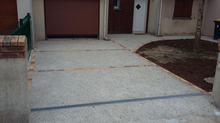 Allée en béton désactivé gravillon roulé et décor en brique jaune flambé